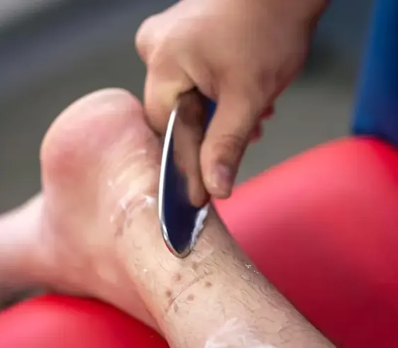 Clinician using an IASTM instrument on a patient's calf