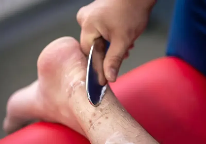 Clinician using an IASTM instrument on a patient's calf