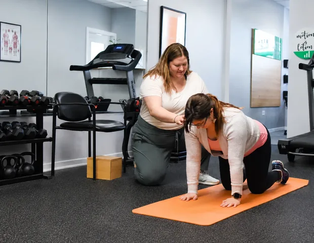 An Elevate clinician coaching a patient through an exercise on the gym floor